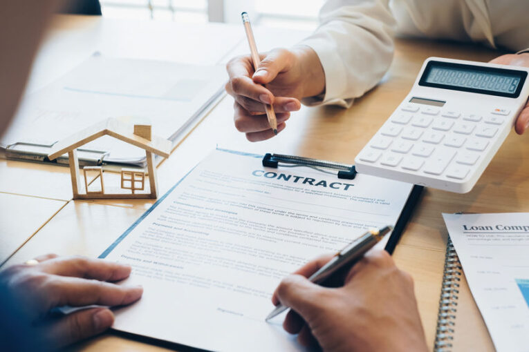 Close up of Business woman pointing and signing agreement for buying house. Bank manager and real estate concept.